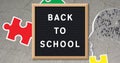 Image of puzzles falling over back to school text on black letter board
