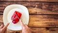 A raw pepper on a plate, being cut with a knife and fork. Selective focus. Copy space