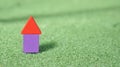 Image of rectangular and triangular shape wood block forming shape of a house on green grass Royalty Free Stock Photo