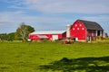 Red barn on farmland with hay bales on feeder in summer