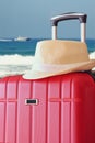 Image of red elegant travel luggage and fedora hat in front of sea. travel and vacation concept Royalty Free Stock Photo