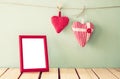 Image of red fabric hearts hanging on rope and blank frame in front of wooden background. retro filtered Royalty Free Stock Photo