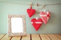 Image of red fabric hearts hanging on rope and blank frame in front of wooden background. retro filtered Royalty Free Stock Photo