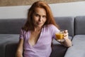 Image of redhead pleased woman drinking juice while sitting on floor Royalty Free Stock Photo