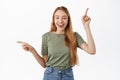 Image of relaxed happy young woman pointing fingers sideways on top and left, smiling and laughing, recommending two Royalty Free Stock Photo