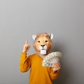 Image of rich man wearing casual sweater and paper king mask, holding his salary, showing dollar banknotes, pointing up at copy