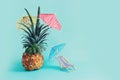 Image with ripe pineapple with parasol and beach chair over blue background. Summer holidays and tropical theme Royalty Free Stock Photo