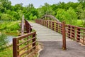 Rusty iron metal walking bridge with yellow paint on pole leading to Canadian geese on grass Royalty Free Stock Photo