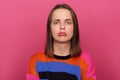 Image of sad depressed stressed woman wearing colorful jumper posing isolated over pink background, looking at camera with pout