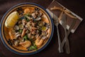 Seafood salad - shrimp, squid and seashells on colored plate with lemon and cutlery on napkin