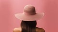 Back of woman wearing wide brimmed sunhat on pink background