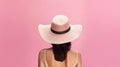 Back of woman wearing wide brimmed sunhat on pink background