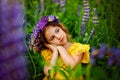 Image with selective focus. On a Sunny summer day, a little girl with a wreath on her head and a yellow dress on a blooming field