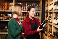 Image of seller and buyer on blurred background of racks with bottles of wine