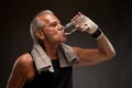 Image of a senior man drinking water after exercising