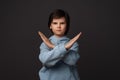 Image of serious boy in casual clothes making X sign with crossed hands, gesturing stop. Human emotions concept Royalty Free Stock Photo