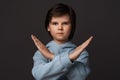 Image of serious boy in casual clothes making X sign with crossed hands, gesturing stop. Human emotions concept Royalty Free Stock Photo