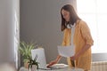 Image of serious concentrated woman holding papers, doing paperwork at workplace in office or at home, standing near table with Royalty Free Stock Photo