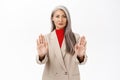Image of serious-looking corporate woman in business, showing stop, rejection prohibit gesture, extending hands forward