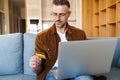 Image of serious man holding credit card and working with laptop