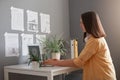 Image of serious woman freelancer wearing yellow shirt having brown hair typing on notebook in office, having concentrated facile