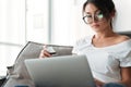 Serious young woman holding debit card using laptop computer. Royalty Free Stock Photo