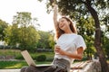 Image of happy modern woman sitting on bench in green park and e Royalty Free Stock Photo