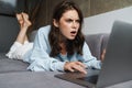 Image of shocked nice woman working with laptop while lying on sofa Royalty Free Stock Photo
