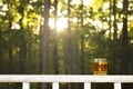 Image of a shot of whiskey on a porch railing in front of the sunset