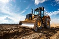 A powerful construction vehicle works on a dirt field. The sky is bright with sun and clouds. This robust machine Royalty Free Stock Photo