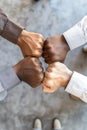 Four individuals from diverse backgrounds unite through a fist bump, symbolizing teamwork, partnership, and shared success in Royalty Free Stock Photo