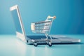 An image showcasing a shopping cart placed on top of a laptop computer, shopping cart and laptop, soft blue background, AI