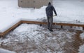 Person shoveling deep snow off a wooden deck