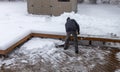 Person shoveling deep snow off a wooden deck