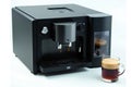 The image shows a black coffee machine next to a cup of coffee on a white surface Royalty Free Stock Photo