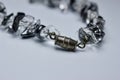 Macro abstract view of a vintage hematite and quartz crystal necklace on white background with tarnished silver clasp