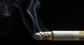 Burning cigarette with smoke against a black background, close-up, harmful habit Royalty Free Stock Photo