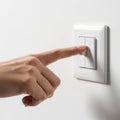 A finger pressing a light switch on a white wall Royalty Free Stock Photo