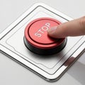 A finger pressing a large red stop button on a control panel Royalty Free Stock Photo