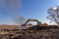 Excavator machinery moving trees and debris into a fire pit