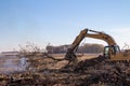 Excavator machinery moving trees and debris into a fire pit