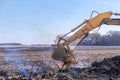 Excavator machinery moving trees and debris into a fire pit