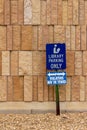 View of a library parking sign in front of an modern limestone wall with rough texture bricks