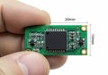 Small electronic module with dimensions displayed next to a human finger for scale Royalty Free Stock Photo