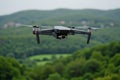 The image shows a DJI Mavic Air drone with camera in the air with trees, hills, and blue sky Royalty Free Stock Photo