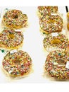 Packaged donuts with colorful sprinkles arranged neatly on white surface for display Royalty Free Stock Photo