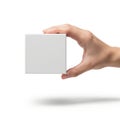A hand holding a small white square object against a white background Royalty Free Stock Photo