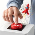 A hand pressing a launch button with a rocket blasting off in the background Royalty Free Stock Photo
