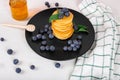 Image shows a homemade fluffy pancake with blueberry and mint on the top; situation is decorated with white wooden table and honey Royalty Free Stock Photo