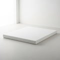 The image shows a large, rectangular, white object with a slightly textured surface, placed on a white floor against a white wall Royalty Free Stock Photo